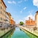 A canal between buildings with a church and a clock tower in the distance